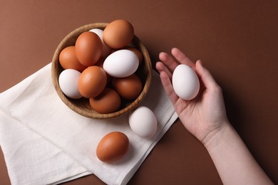 Photo of Woman with raw eggs on brown background, closeup