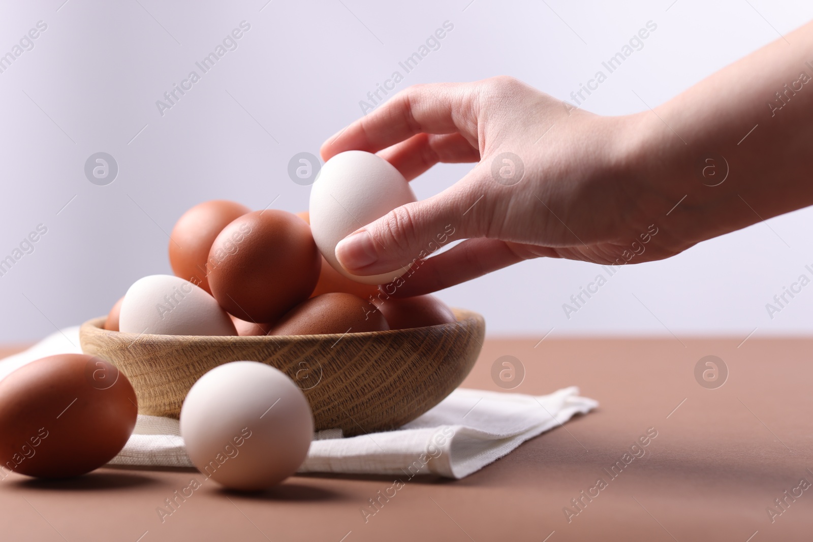 Photo of Woman with raw eggs at brown table, closeup