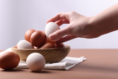 Photo of Woman with raw eggs at brown table, closeup