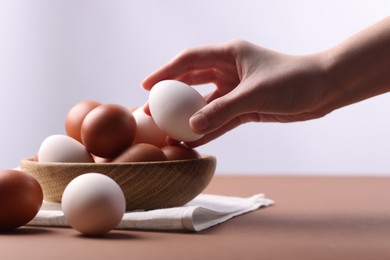 Photo of Woman with raw eggs at brown table, closeup