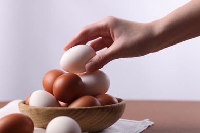 Photo of Woman with raw eggs at brown table, closeup