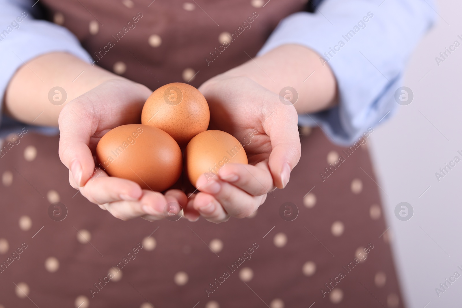 Photo of Woman with raw eggs on light background, closeup