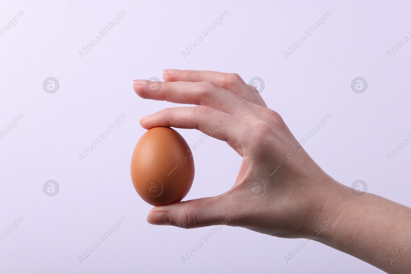 Photo of Woman holding raw egg on light background, closeup