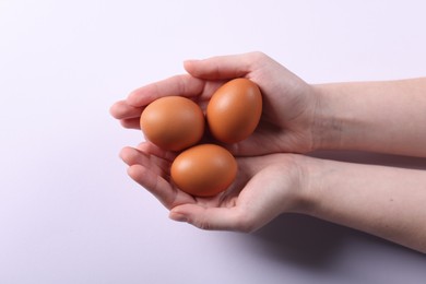 Photo of Woman with raw eggs on light background, closeup