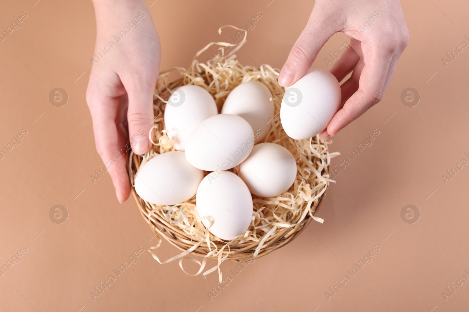 Photo of Woman with raw eggs on beige background, top view