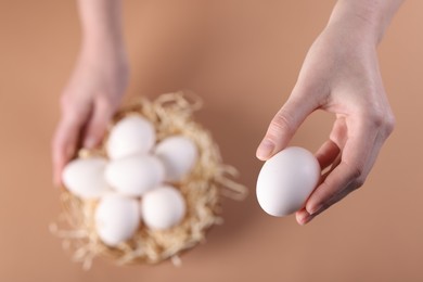 Photo of Woman with raw eggs on beige background, top view