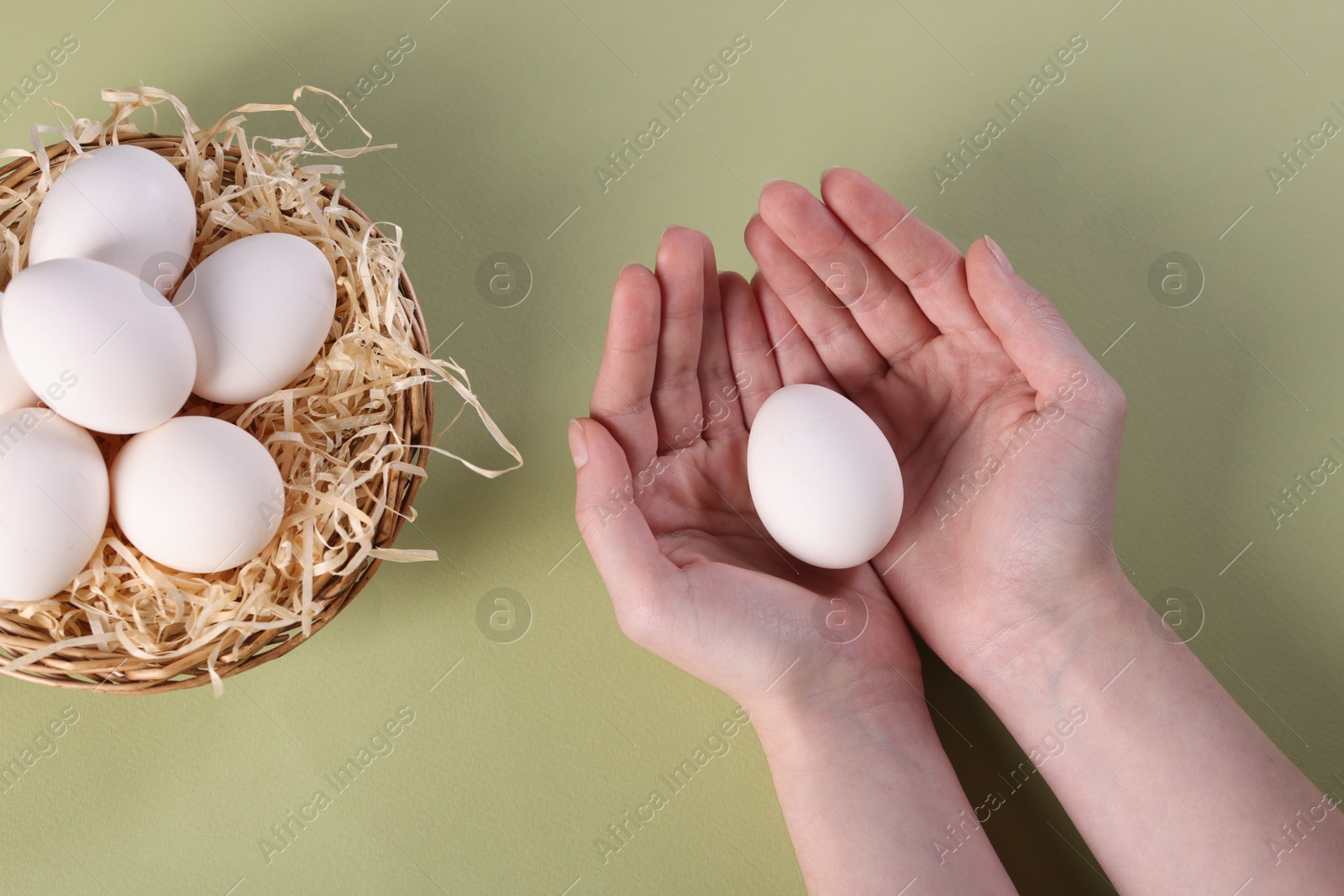 Photo of Woman with raw eggs on olive background, top view