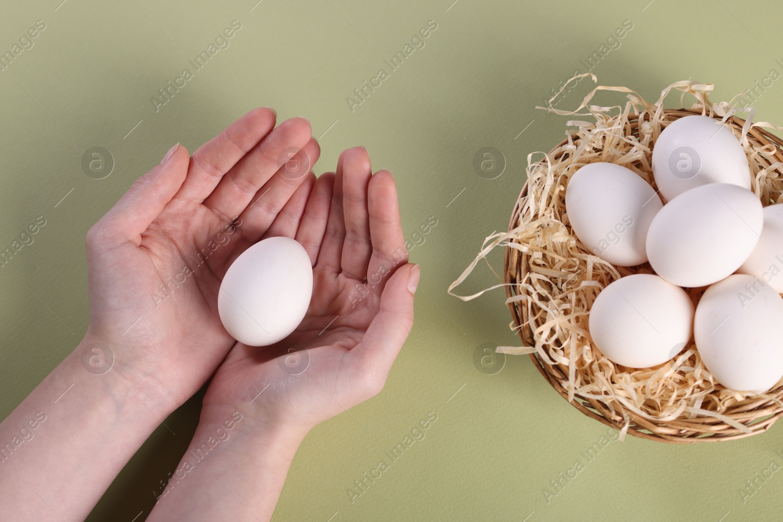 Photo of Woman with raw eggs on olive background, top view