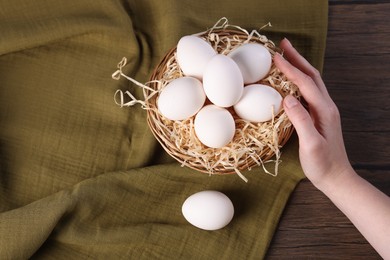 Photo of Woman with raw eggs at wooden table, closeup