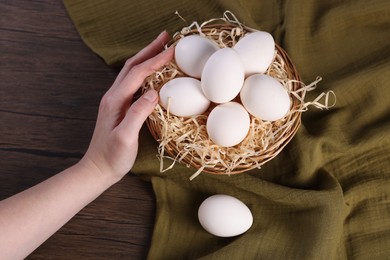 Photo of Woman with raw eggs at wooden table, closeup