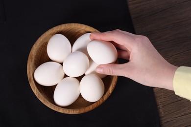 Photo of Woman with raw eggs at wooden table, top view