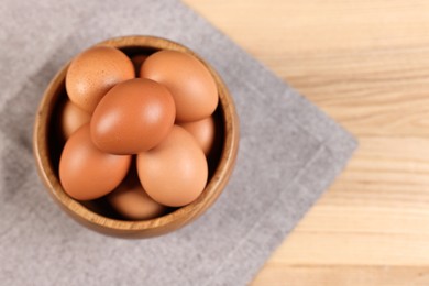 Photo of Raw eggs in bowl on wooden table, top view