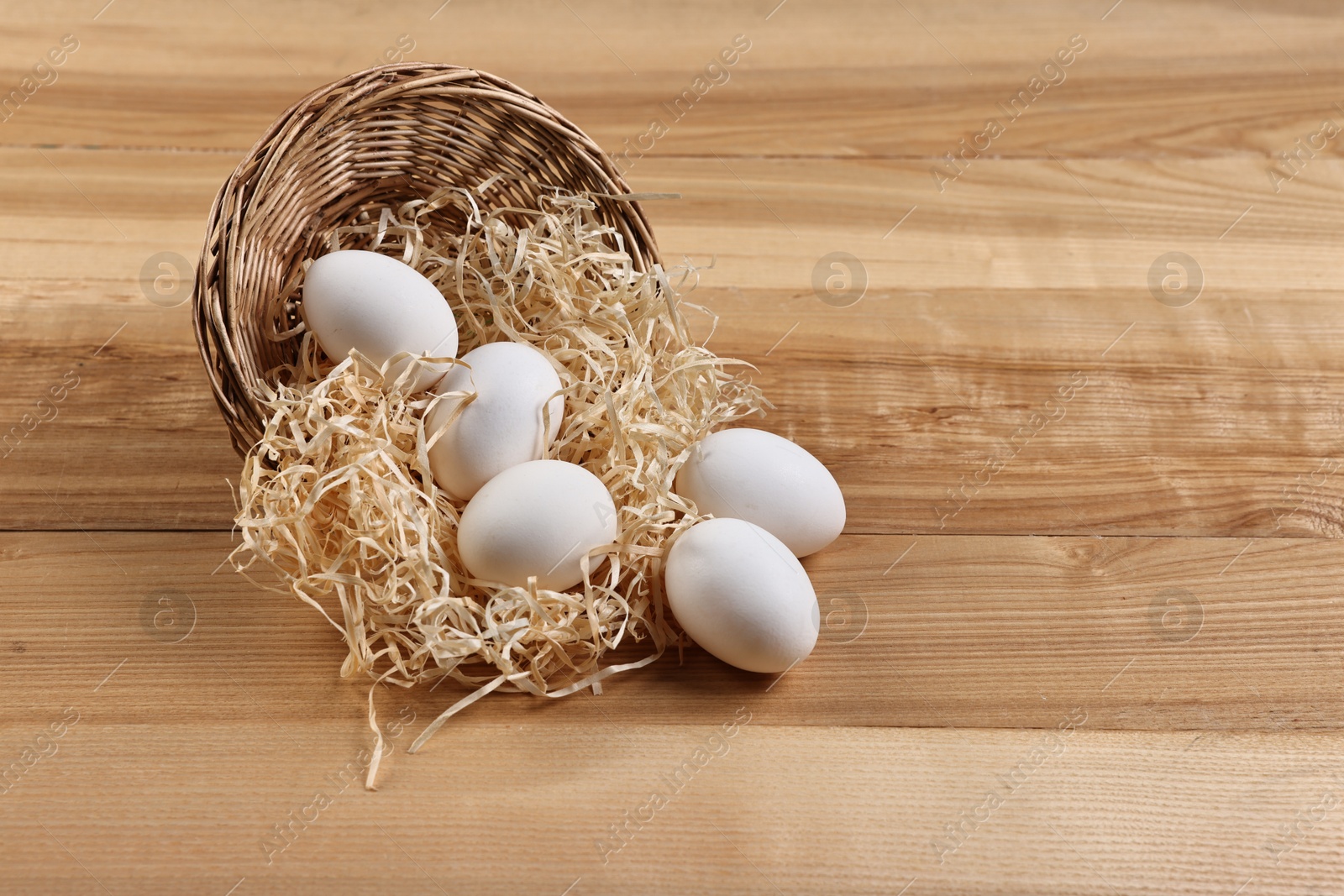 Photo of Basket with raw eggs on wooden table. Space for text