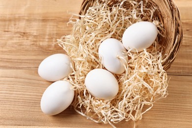 Photo of Basket with raw eggs on wooden table, closeup