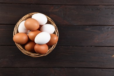 Photo of Raw eggs in basket on wooden table, top view. Space for text