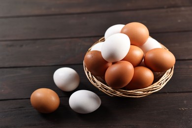 Photo of Raw eggs in basket on wooden table, closeup. Space for text