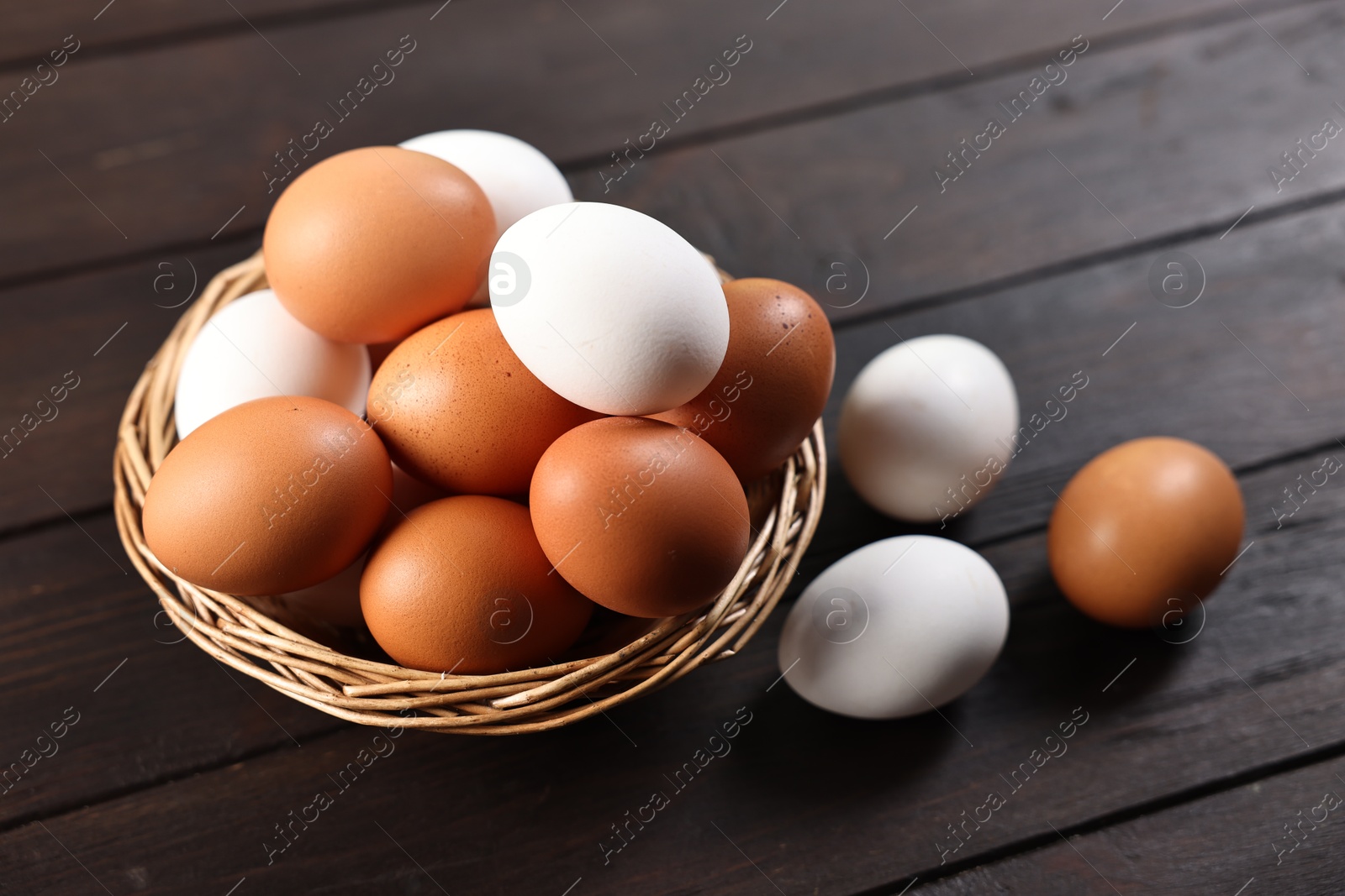 Photo of Raw eggs in basket on wooden table, closeup