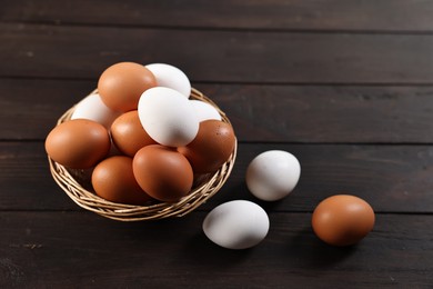 Photo of Raw eggs in basket on wooden table, closeup. Space for text