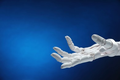 Photo of Artificial intelligence. Robot hand gesturing on dark blue background, space for text