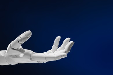 Photo of Artificial intelligence. Robot hand gesturing on dark blue background, space for text