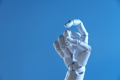 Photo of Artificial intelligence. Robot hand gesturing on blue background, space for text