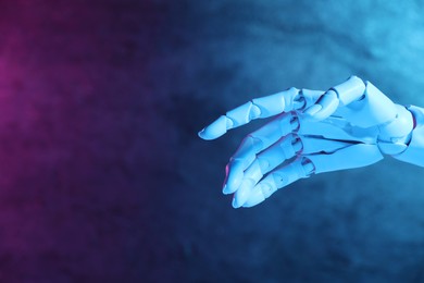 Photo of Artificial intelligence. Robot hand gesturing on blurred background in neon lights, space for text