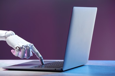 Photo of Artificial intelligence. Robot hand with laptop on table in neon lights