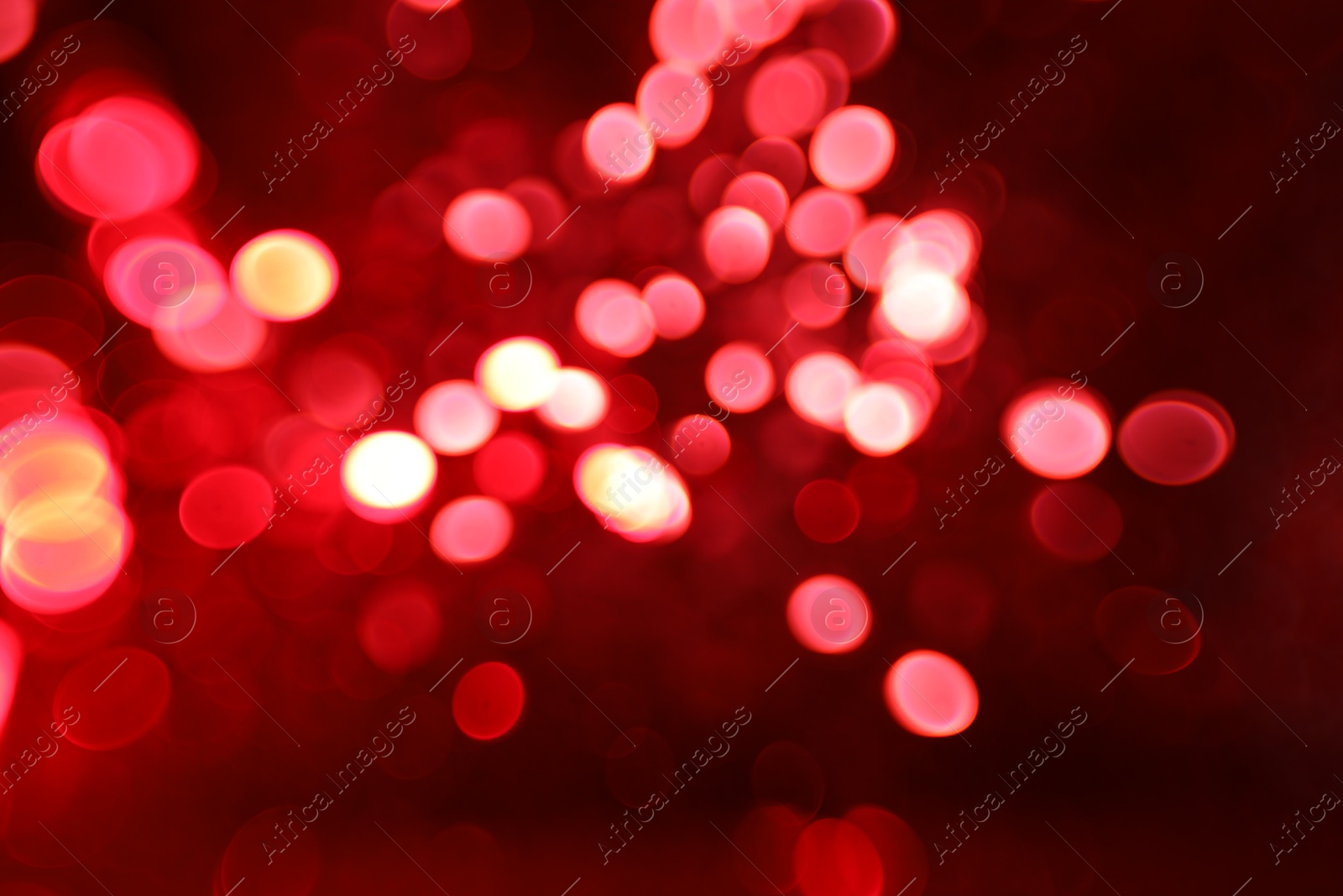 Photo of Blurred view of festive lights on red background. Bokeh effect