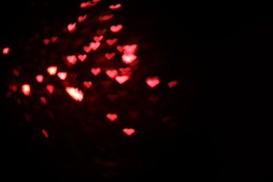 Photo of Romantic decor. Blurred view of heart shaped lights on black background, space for text. Bokeh effect