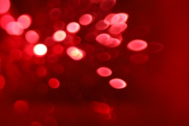 Photo of Blurred view of festive lights on red background. Bokeh effect