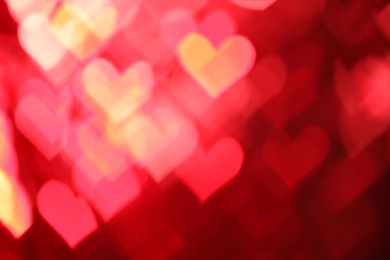 Photo of Romantic decor. Blurred view of heart shaped lights on red background, bokeh effect