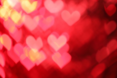 Photo of Romantic decor. Blurred view of heart shaped lights on red background, bokeh effect