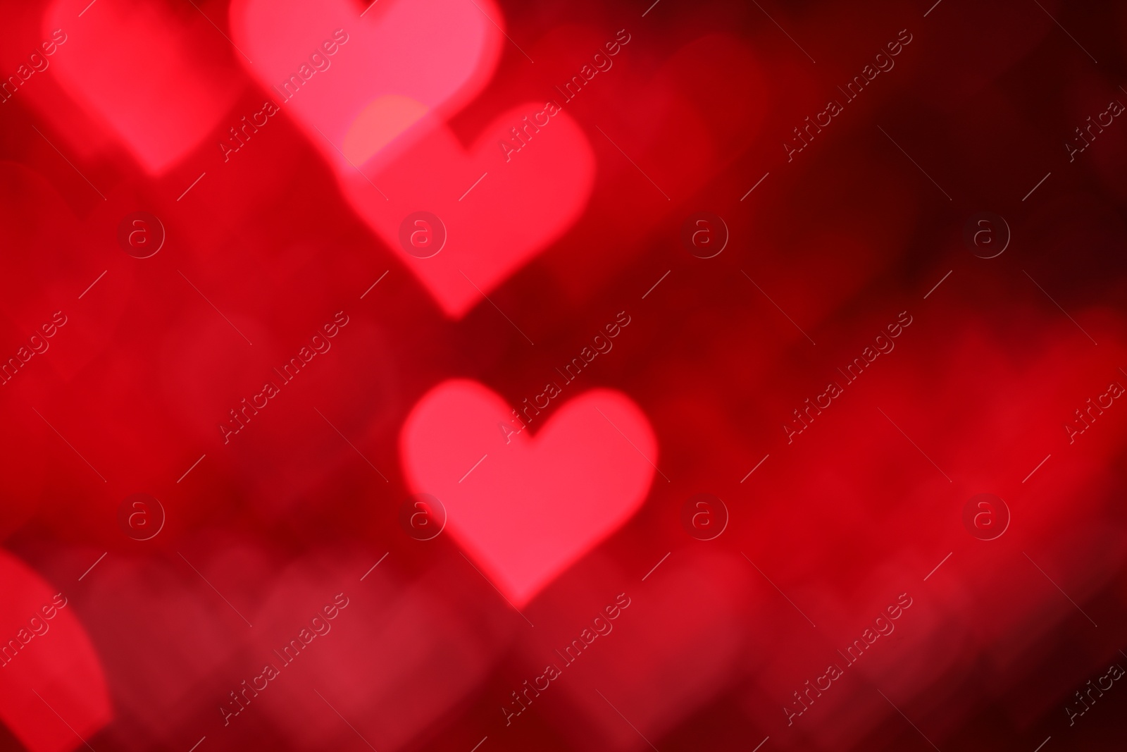 Photo of Romantic decor. Blurred view of heart shaped lights on red background, bokeh effect