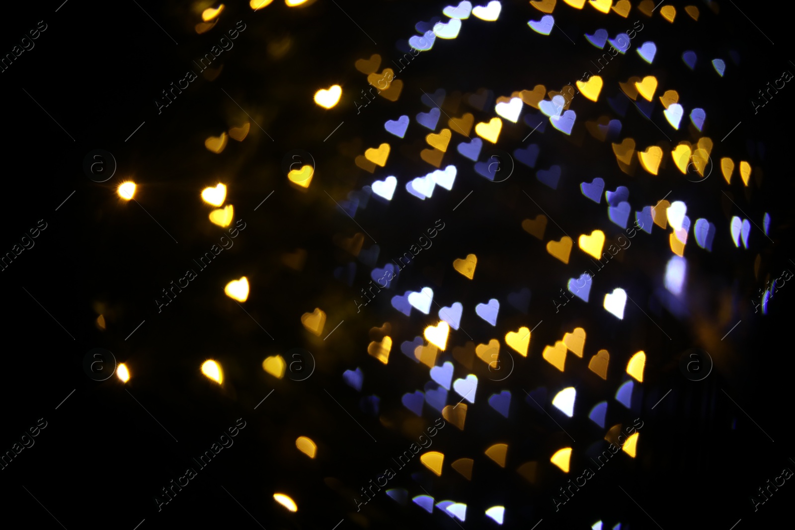 Photo of Romantic decor. Blurred view of heart shaped lights on black background, bokeh effect