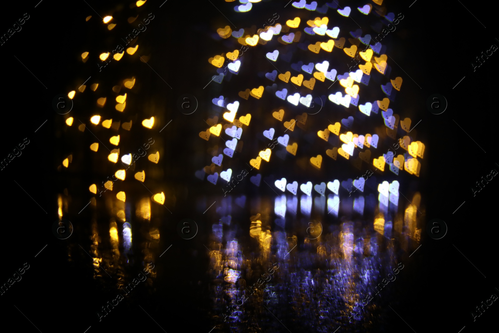 Photo of Romantic decor. Blurred view of heart shaped lights on black background, bokeh effect