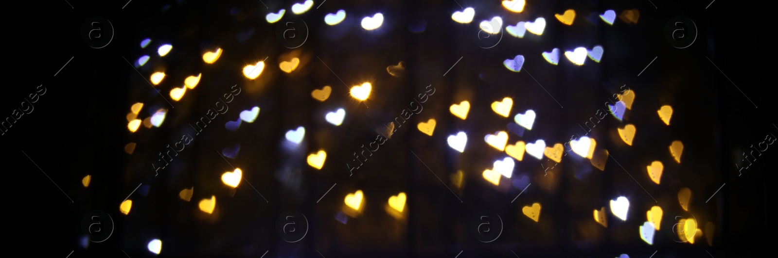 Photo of Romantic decor. Blurred view of heart shaped lights on black background, bokeh effect