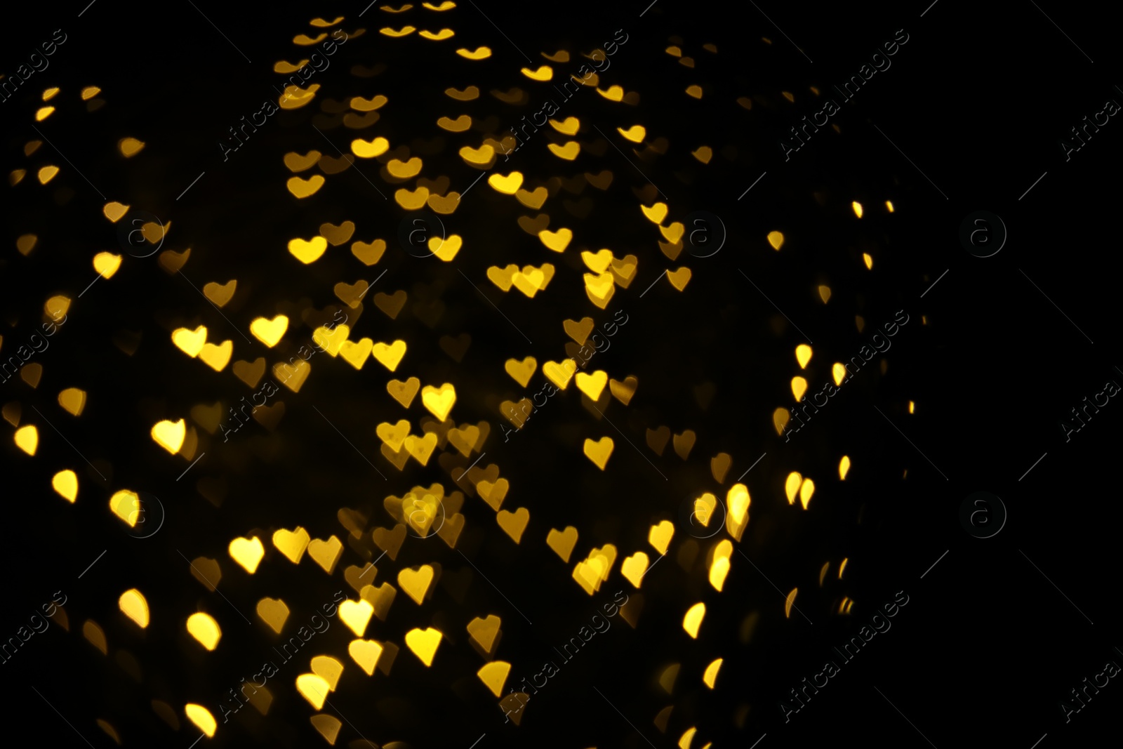 Photo of Romantic decor. Blurred view of heart shaped lights on black background, bokeh effect