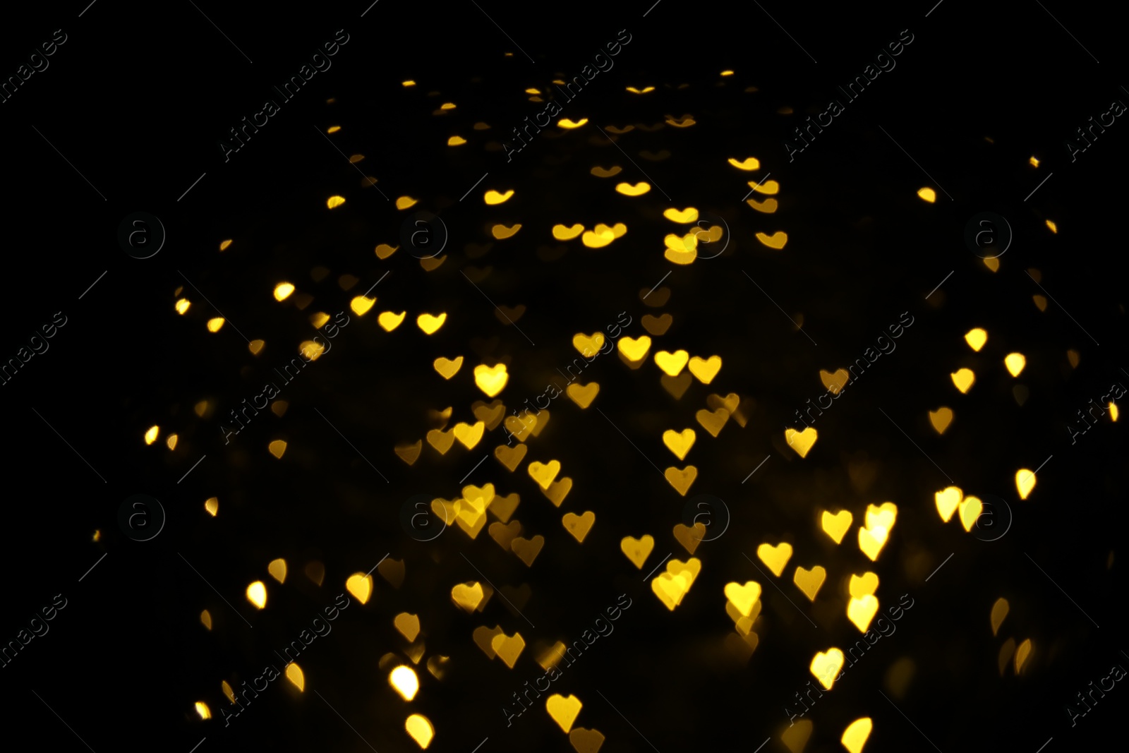 Photo of Romantic decor. Blurred view of heart shaped lights on black background, bokeh effect