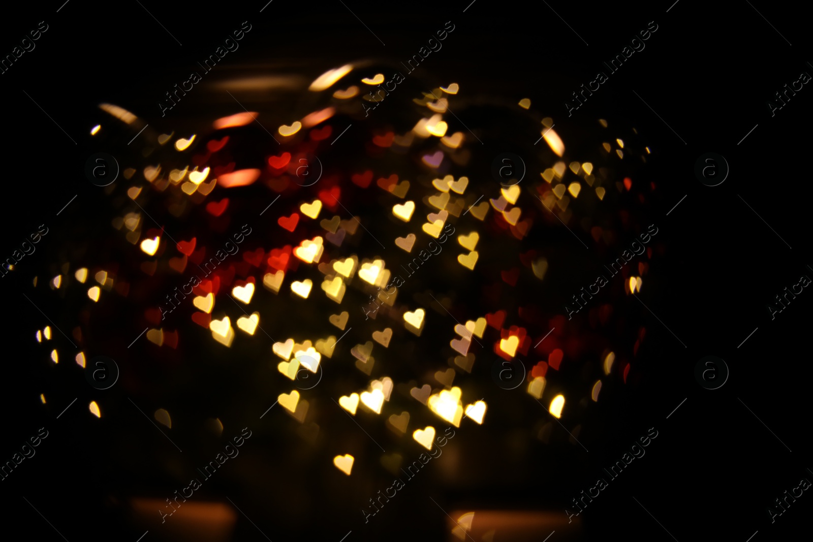 Photo of Romantic decor. Blurred view of heart shaped lights on black background, bokeh effect