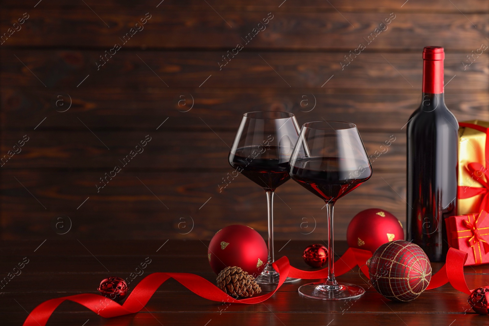 Photo of Red wine and beautiful Christmas decor on wooden table. Space for text