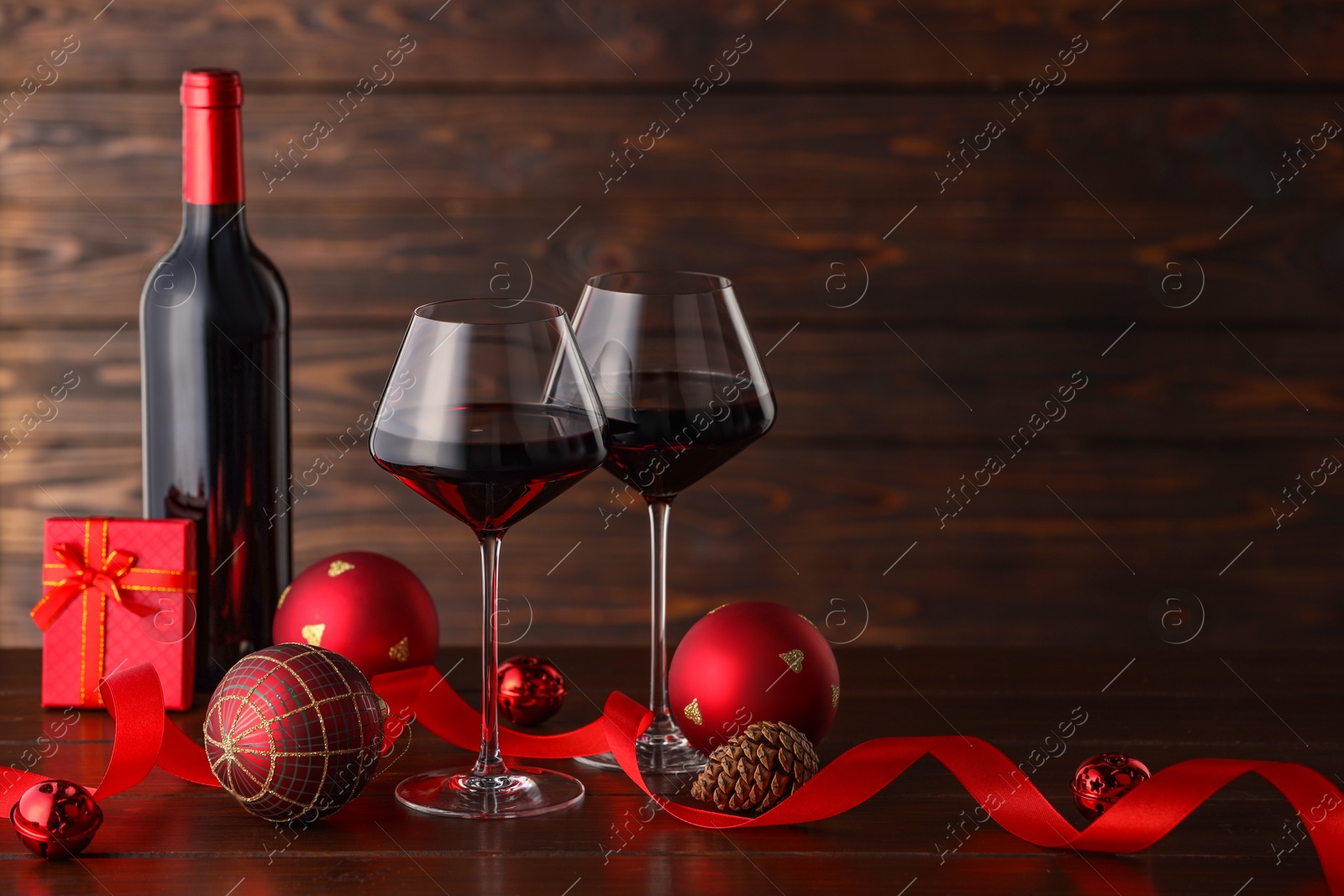 Photo of Red wine and beautiful Christmas decor on wooden table. Space for text