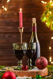 Photo of Red wine and beautiful Christmas decor on wooden table against blurred festive lights