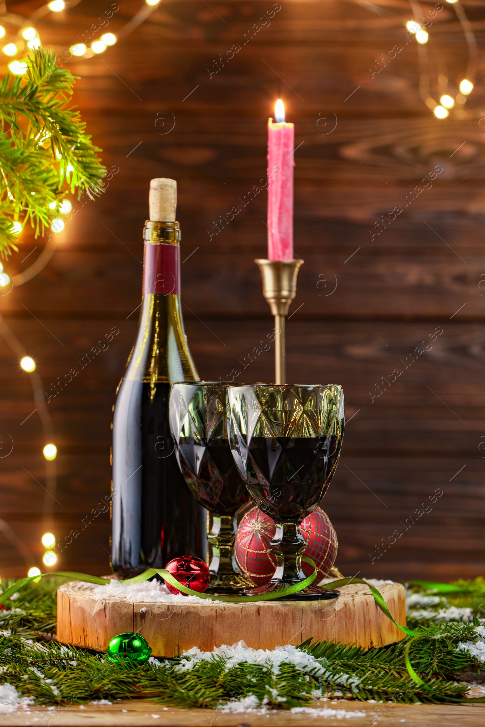 Photo of Red wine and beautiful Christmas decor on wooden table against blurred festive lights