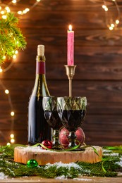 Photo of Red wine and beautiful Christmas decor on wooden table against blurred festive lights