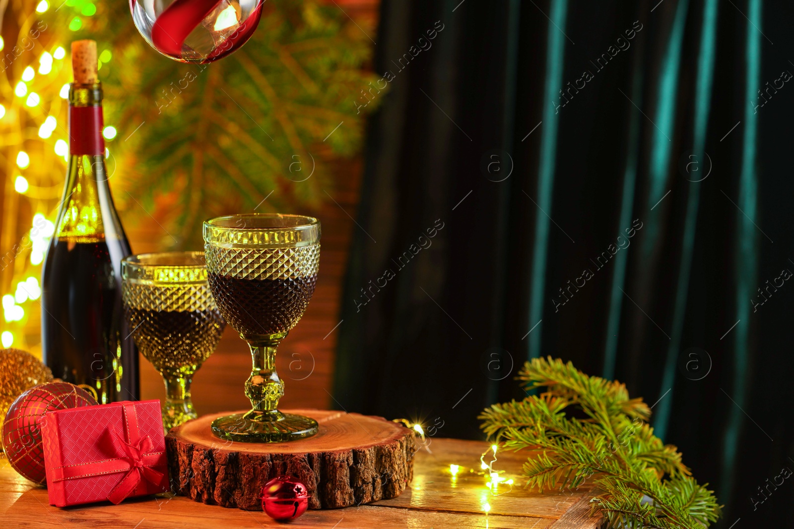 Photo of Red wine and beautiful Christmas decor on wooden table against blurred festive lights. Space for text