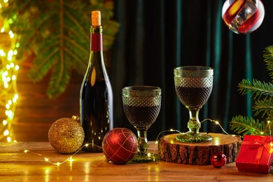 Photo of Red wine and beautiful Christmas decor on wooden table against blurred festive lights