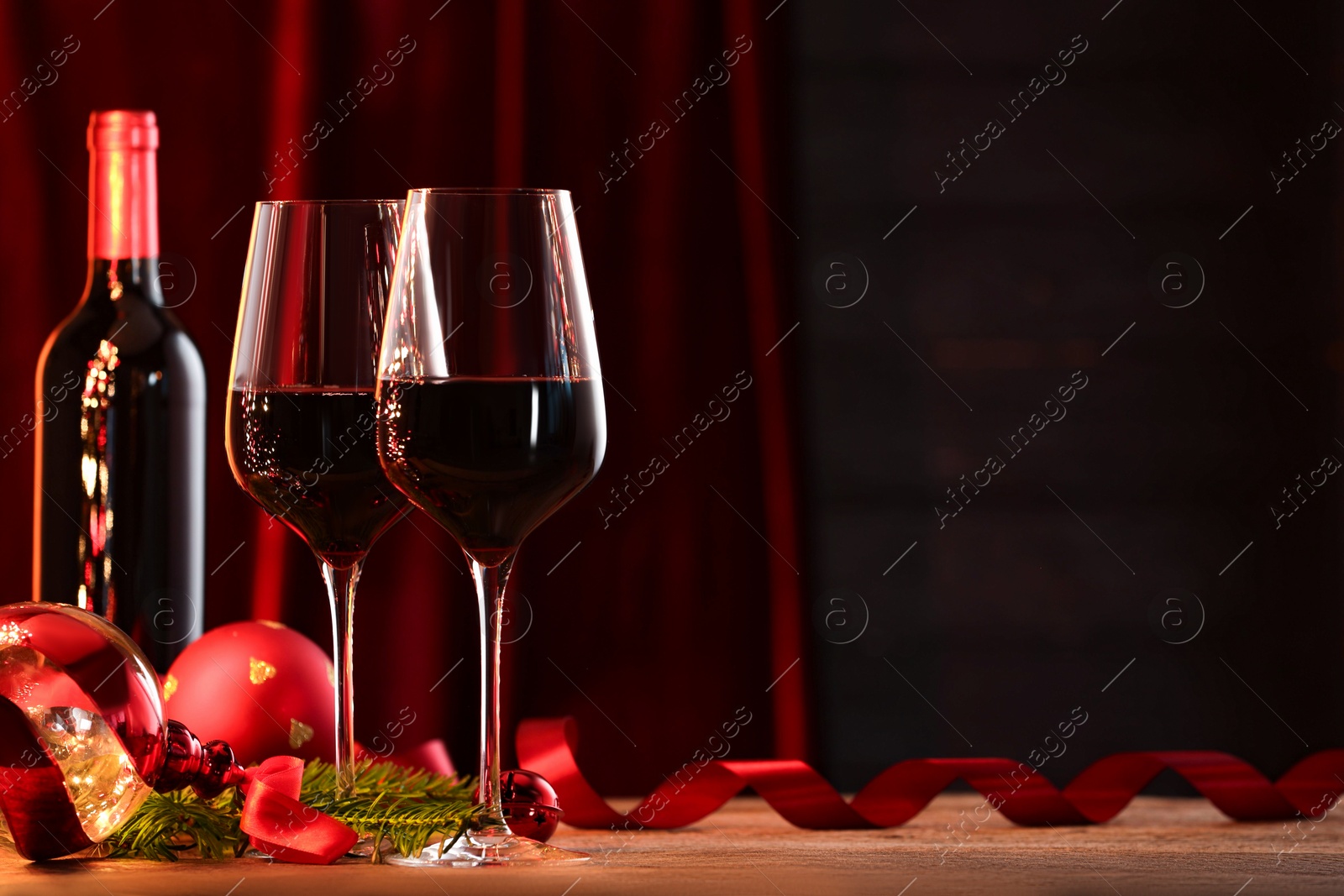 Photo of Red wine and Christmas decor on wooden table. Space for text