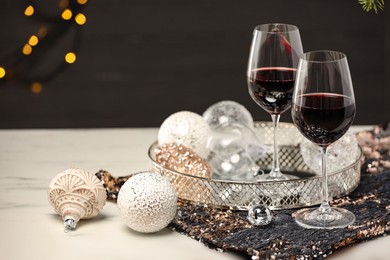 Photo of Glasses with red wine and beautiful Christmas decor on white table