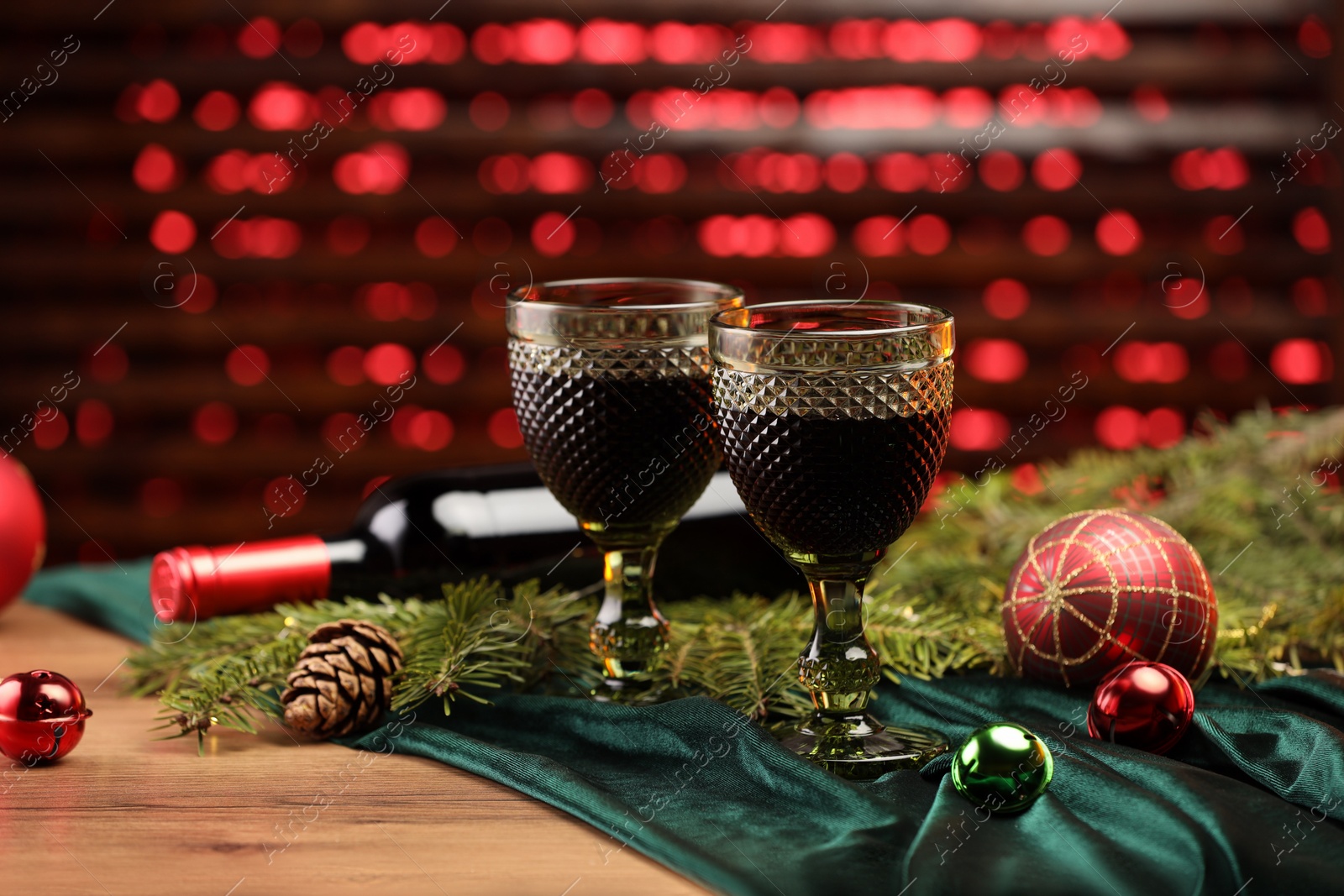 Photo of Glasses with red wine and beautiful Christmas decor on wooden table