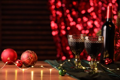 Photo of Red wine and beautiful Christmas decor on wooden table. Space for text